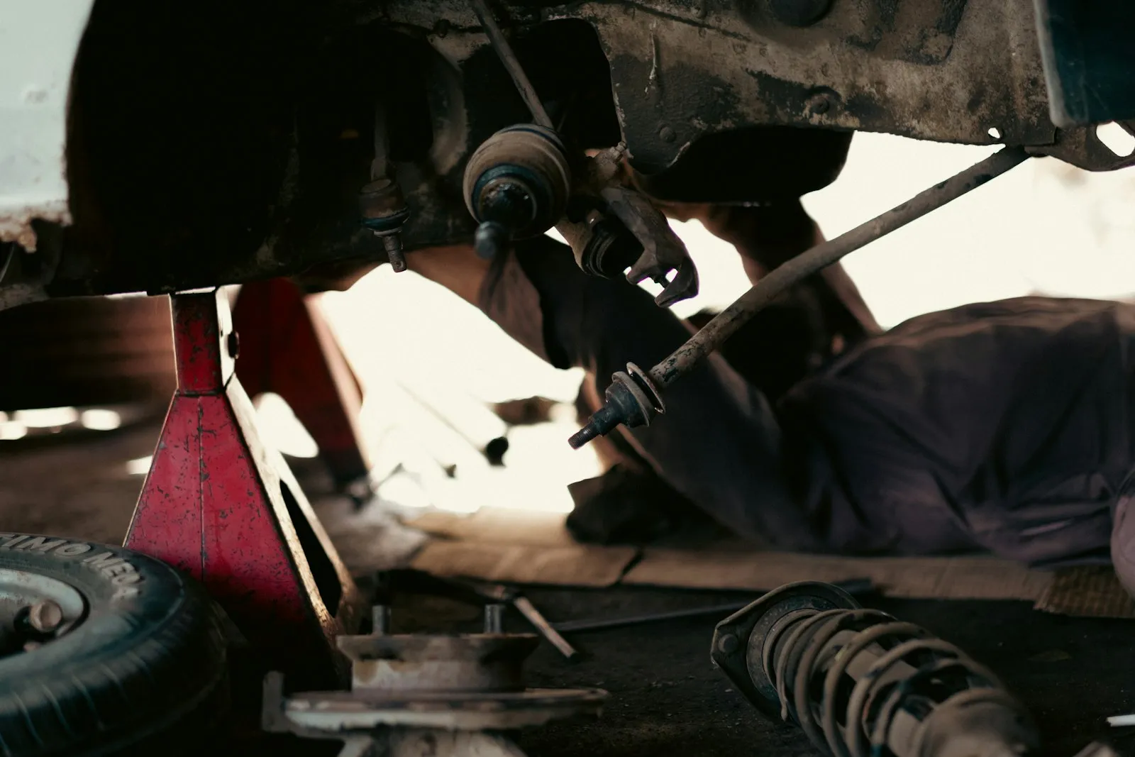 A 5 Points technician working under a vehicle on the lift